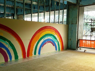 壁に赤、オレンジ、黄色、緑、青、紫の鮮やかな色で描かれた虹が2つ描かれている写真