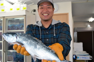 男性が笑顔で大きな魚を両手で持ってカメラに向かって見せている写真