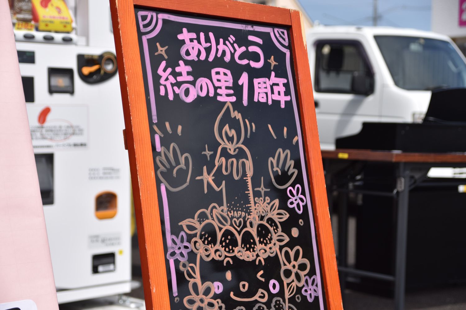「ありがとう 結の里1周年」と書かれた手描きのカラフルなイラストが描かれている黒板をアップで撮影した写真