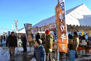 串カキ屋と書かれたののぼりが立ち並ぶテントに多くの来場者が行き交い、にぎやかな市場の雰囲気が広がっているおすばで祭り福興市の写真