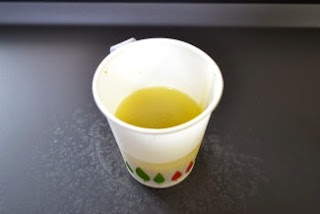 白と緑の模様が入った紙コップの中に、黄色っぽい液体の石けんが注がれて置かれている写真