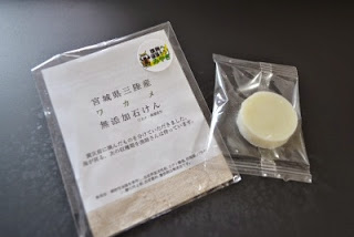 「宮城県三陸産ワカメ無添加石けん」と書かれた袋と、中に入っている丸い石けんが並べて置かれている写真