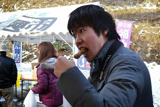 若い男性が串焼きを勢いよくかじっている様子を写した写真