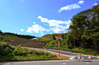 分岐点のある交差点の先に草木に覆われた丘が工事され斜面に整えられている写真