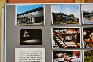 茶色の外壁の2階建ての建物外観や、民宿の室内などの写真が並べられた展示パネルの写真