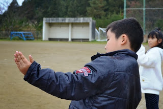 外で子どもが両手を広げて糸の張り具合を確かめている様子の写真