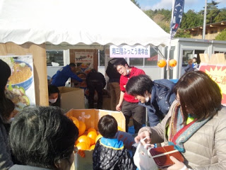 白いテントの下で、南三陸ふっこう青年会が主催するブースに多くの親子連れが集まり、イベントを楽しんでいる写真
