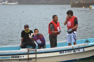 濡れた参加者たちが小さな船に乗って笑顔で楽しそうに話したりしている写真