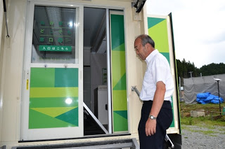 移動銀行車の入口が半開きになっていて、男性がせり出した部分の様子を見せている写真