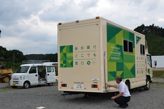移動銀行車の後部から全体を写しており、後部扉が下ろされた撤収作業が完了した状態を示した写真