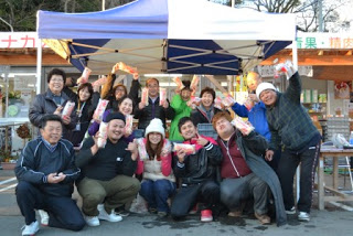 歌手の奥華子さんが写真中央に座り、関係者の方々が集まって笑顔で写っている記念写真