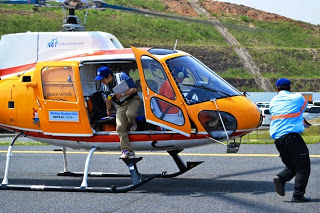 地面に着陸したオレンジ色のヘリコプターから医療スタッフが降りて患者搬送の準備をしている写真