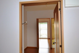 室内のドアがいくつか開いており、奥の窓から外の明るい光が差し込んでいる様子を玄関側から見た写真