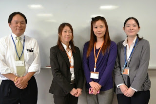 ホワイトボードの前に白いシャツを着た男性と、3人の女性講師が並んでいる写真