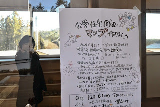 建物内のガラスに「公営住宅周辺マップを作りましょう」と書かれた手書きのポスターが貼られた写真