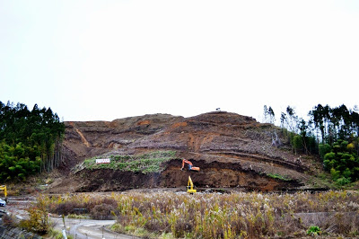 大規模に山が削られ、重機で土地造成工事が行われている最中の斜面の写真