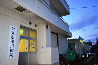 夕方の空の下、「公立志津川病院」と書かれた白い外壁の建物の入口の写真