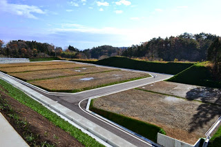 平らにならされた複数の区画と舗装された道路が整然と配置され、住宅が建つ前の更地状態が広がっている写真