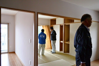 室内で男性数人が内見をしており、畳の部屋や収納スペースを確認している様子が写っている写真