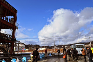 真っ白な雲の青空の中建設現場を見学している参加者の人たちの写真
