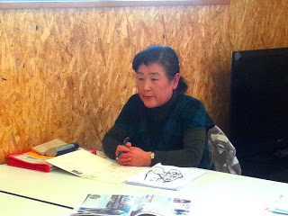 机に書類を広げて、席についている関仲松敏子先生の写真