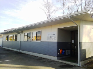 白とグレーの外壁を持つ長方形の建物の歌津公民館の外観写真