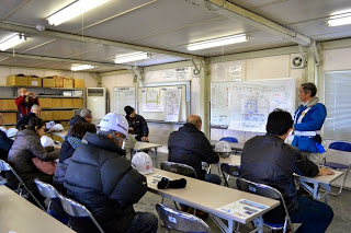 室内で長机に座り説明を聞いている参加者の人たちの写真