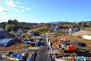 中央の仮設道路を中心に、両側で複数の重機が作業を行っている造成工事が進行中の様子の写真