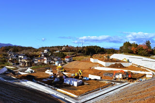 傾斜のある造成地で、重機が複数台稼働しながら土地を平坦に整備している造成工事の様子の写真