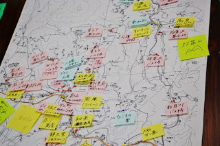 白地図の上にカラフルな付箋がたくさん貼られ、地名やコメントが手書きで記されているマップ作成中の写真