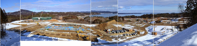 奥に海が見え、雪が残る広大な現場に戸倉地区の高台移転工事が進められている様子をパノラマで写した写真