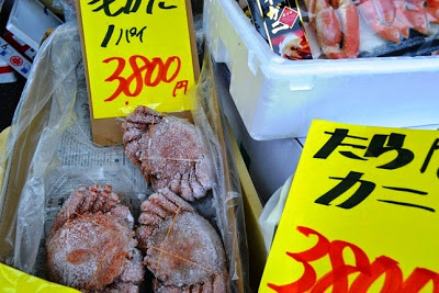 「毛ガニ1パイ3800円」「たらばカニ3800円」と大きく書かれた黄色い値札の下に、冷凍されたカニが発泡スチロールの箱に入れられて販売されている海産物販売ブースの写真