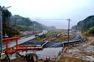 鳥居の側の道路工事の現場で、工事用車両が配置された道路工事中の写真