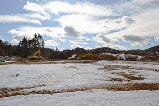 雪が残る中、周りに重機がならび、平面になっている広い土地を移した写真