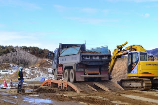 大型トラックにショベルカーで土を運んでいる工事現場の写真