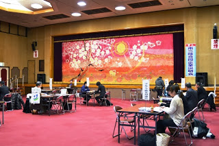 広々とした会場に多くのテーブルが並び、参加者が複数のテーブルに分かれて座り合同企業説明会が室内で行われている様子の写真