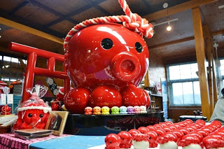 店内に赤い鳥居と一緒に大きなオクトパス君の置物が置かれ、周囲に沢山の小さなオクトパス君の置物が並べられている写真