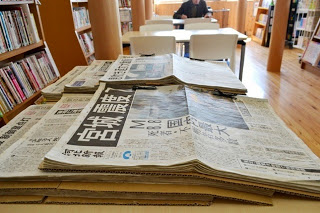 東日本大震災に関する新聞が複数折り重なってテーブルの上に置かれていている様子の写真