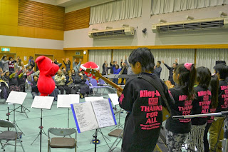 舞台では楽器の演奏が行われ、客席の横では千葉県の公式マスコットキャラクター「チーバくん」と観客が一緒に手を挙げて体を動かしながら音楽を楽しんでいる音楽会の様子の写真