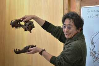 講師の小田隆先生がティラノサウルスの模型の頭骨を両手に持って説明している様子の写真