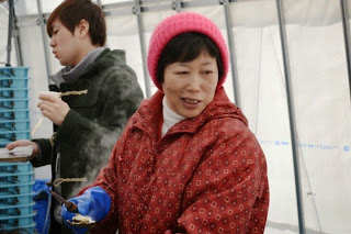 ピンクのニット帽をかぶった村岡絹子さんの写真