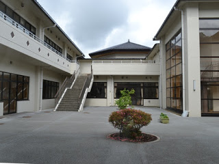 白い外壁の建物に囲まれた中庭にプランターや植栽が整備されており、外階段が建物2階に続いている写真