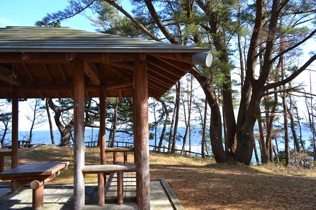 東屋から奥に海が見えるキャンプ場の写真