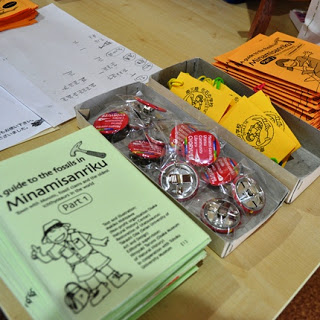 「Minamisanriku」のガイドブックやバッジ、パンフレットなどがテーブルに並べられている様子の写真