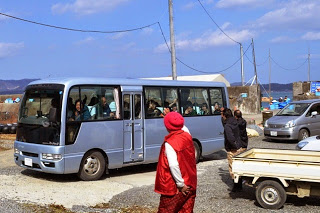 マイクロバスを見送る村岡絹子さんの後姿を写した写真