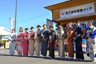 「南三陸町産業フェア」のステージ前に、華やかな着物姿の女性たちが横一列に並んでいる写真
