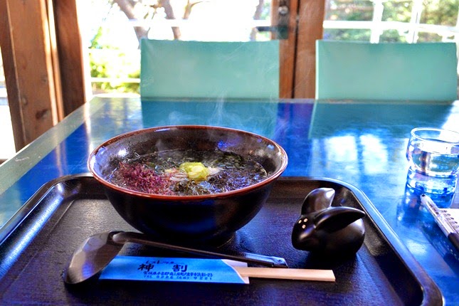湯気が立つ温かい麺料理の丼が載ったお盆の上に、お玉、割り箸、うさぎの形をした箸置きが並べられ、テーブルに置かれている様子を写した写真