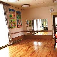 フローリングの部屋で、壁には色とりどりの絵が飾られ、大きな鏡が設置されている写真