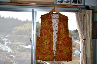 オレンジ色のちゃんちゃんこが窓際に吊るされている写真