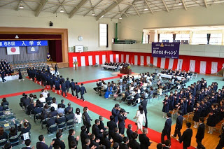 在校生や保護者の方々が拍手で迎えるなか、ステージへと続くレッドカーペット上を新入生が入場している様子の写真